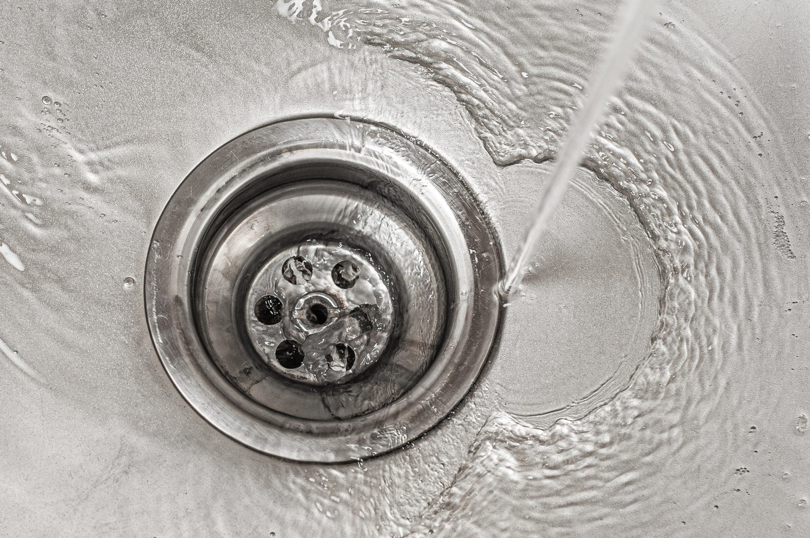 Water swirling into a stainless steel kitchen sink drain