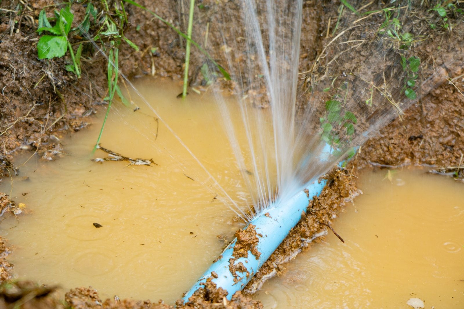 Burst water line spraying water into a muddy excavation